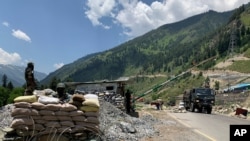 FILE - Indian paramilitary soldiers keep guard as an Indian army convoy moves along the Srinagar-Ladakh highway at Gagangeer, India, June 18, 2020, as a standoff between India and China over the Himalayan Galwan Valley escalates.
