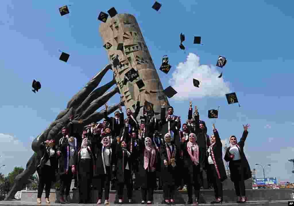 University of Baghdad graduates throw their caps in the air next to the &#39;save Iraqi culture&#39; monument, in Baghdad.