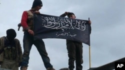 FILE - Rebels from al-Qaida affiliated Jabhat al-Nusra waving their brigade flag.