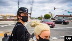 Mshoni wa nguo Flor Hernandez akiuza maski mitaani baada ya kupoteza ajira, wakati wa mlipuko huu wa COVID-19, Los Angeles, California, April 2, 2020.(Photo by Apu GOMES / AFP)