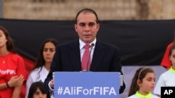 FILE - Jordan's Prince Ali bin al-Hussein, flanked by school-age soccer players in uniforms, speaks during an event at a Roman amphitheater in Amman, Jordan, Sept. 9, 2015. 