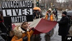 FILE - A person holds a sign during an anti-vaccine mandate protest ahead of the possible termination of New York City employees due to their vaccination status, in New York City, Feb. 7, 2022.