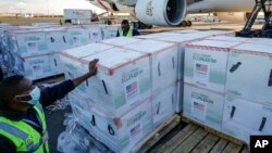 FILE: An airport worker stands next to boxes of Moderna coronavirus vaccine, donated by the U.S. government via the COVAX facility, after their arrival at the airport in Nairobi, Kenya on Aug. 23, 2021. Moderna announced building a Nairobi vaccine plant on March 30, 2023.