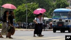 Pedestrians use umbrellas to protect themselves from sun as they cross a road in downtown Yangon, Myanmar on Thursday, April 8 ,2010. 