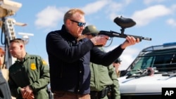 Acting Secretary of Defense Patrick Shanahan, center, fires a modified paint ball gun during a tour of the U.S.-Mexico border at Santa Teresa Station in Sunland Park, N.M., Feb. 23, 2019.