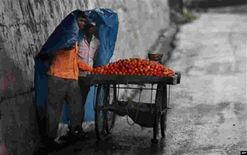 Vendors use a plastic sheet to shelter themselves from the rain in Jammu, India, Friday, July 29, 2011. Monsoon rains, that lash India from June to September, are considered crucial for farmers whose crops feed millions of people. (AP Photo/Channi Anand)