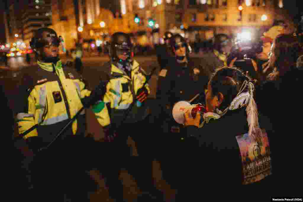 Sur la place Franklin, une indienne d'une réserve se tient devant la police, à Washington DC, le 20 janvier 2017. (VOA/Nastasia Peteuil)