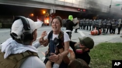 Protesters help a woman who was hit in the throat with a rubber bullet during a demonstration next to the city of Miami Police Department, May 30, 2020, downtown in Miami.