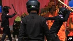 Security officers try to beat Buddhist monks who took part in a rally of the Cambodian National Rescue Party in Phnom Penh, Cambodia, Saturday, Jan. 4, 2014.