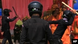 Security officers try to beat Buddhist monks who took part in a rally of the Cambodian National Rescue Party in Phnom Penh, Cambodia, Saturday, Jan. 4, 2014.