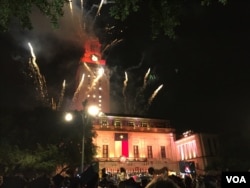 美国德克萨斯大学奥斯汀分校的毕业典礼上，礼花绽放，灯光辉映，地标性建筑顶部呈现橙色。（2017年5月20日）