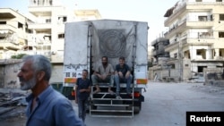 People sit on a Syrian Arab Red Crescent truck, which is part of an aid convoy in the rebel held besieged Harasta area, in the eastern Damascus suburb of Ghouta, Syria, June 19, 2017. Rebel fighters and their families are preparing to leave Harasta for other rebel-held areas.