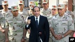 Egyptian President Abdel-Fattah el-Sissi speaks ahead of a military funeral for troops killed in an assault in the Sinai Peninsula, as he stands with army commanders, in Cairo, Egypt, Oct. 25, 2014.