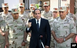 FILE - In this photo provided by Egypt's state news agency MENA, Egyptian President Abdel Fattah el-Sissi, center, speaks in front of the state-run TV ahead of a military funeral for troops killed in an assault in the Sinai Peninsula, as he stands with army commanders in Cairo, Egypt, Saturday, Oct. 25, 2014.