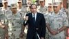 In this photo provided by Egypt's state news agency MENA, Egyptian President Abdel-Fattah el-Sissi speaks in front of the state-run TV ahead of a military funeral for troops killed in an assault in the Sinai Peninsula, as he stands with army commanders in