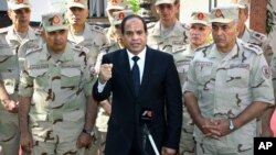 In this photo provided by Egypt's state news agency MENA, Egyptian President Abdel-Fattah el-Sissi speaks in front of the state-run TV ahead of a military funeral for troops killed in an assault in the Sinai Peninsula, as he stands with army commanders in