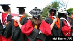 FILE - In this May 15, 2016 file photo, students embrace as they arrive for the Rutgers graduation ceremonies in Piscataway, New Jersey.