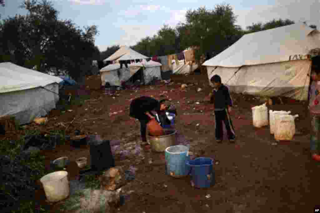 A Syrian girl, who fled her home with her family in Idlib, collects water at a camp for displaced Syrians in the village of Atmeh, Syria, Thursday, Dec. 13, 2012. (AP Photo/Muhammed Muheisen)
