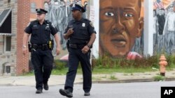 Deux policiers de Baltimore patrouillent près d'une fresque représentant Freddie Gray, le 27 juillet 2016.