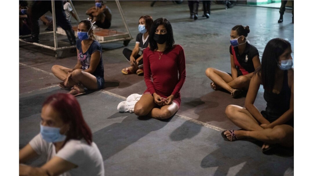 Las mujeres que fueron detenidas por no cumplir con las regulaciones de COVID-19 o asistir a fiestas en la cuadra, se sientan dentro de un coliseo en el barrio de Petare en Caracas, Venezuela.