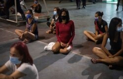 Las mujeres que fueron detenidas por no cumplir con las regulaciones de COVID-19 o asistir a fiestas en la cuadra, se sientan dentro de un coliseo en el barrio de Petare en Caracas, Venezuela.