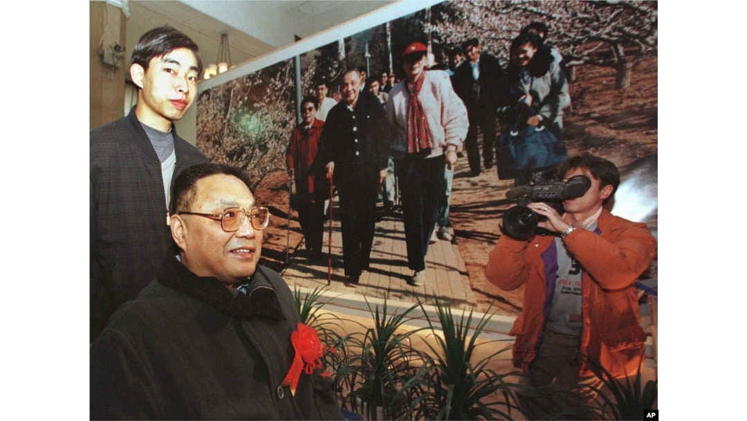 中国已故领导人邓小平的儿子邓朴方1998年2月18日在北京军事博物馆举办的展览中观看了他父亲的一张大照片，由他的妹妹邓琳拍摄。