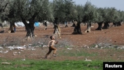 FILE - An internally displaced Syrian boy runs in a olive field, in Azaz, Syria, March 11, 2020.