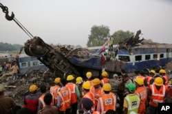 Rescuers search through debris after 14 cars of an overnight passenger train rolled off the track near Pukhrayan village Kanpur Dehat district, Uttar Pradesh state, India, Nov. 20, 2016.