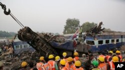 Tim SAR melakukan pencarian korban di antara reruntuhan gerbong kereta yang hancur akibat keluar dari jalur rel di dekat desa Pukhrayan distrik Kanpur Dehat, negara bagian Uttar Pradesh, India, 20 November 2016. (AP Photo/Rajesh Kumar Singh)