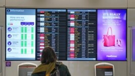 A passenger looks at a departures board at London Heathrow Airport's T3 as the US reopens its borders to UK visitors in a significant boost to the travel sector, in London, Monday, Nov. 8, 2021. (Anthony Upton/PA via AP)