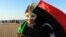 A girl, wearing a mask and holding the national flag, smiles as she marks the second anniversary of the country's revolution in Benghazi Feb. 16, 2013. 