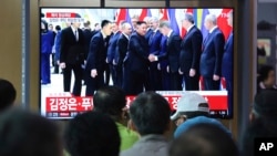 People watch a TV screen showing North Korean leader Kim Jong Un, center, and Russian President Vladimir Putin, center left, in Russia during a news program at the Seoul Railway Station in Seoul, South Korea, Thursday, April 25, 2019. (AP Photo/Ahn Young-