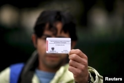 Omar shows the back of his Austrian migrant card in Traiskirchen, Oct. 13, 2015.