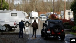 Residents of the Riverview RV Park, survey floodwaters Wednesday, Dec. 9, 2015, in Puyallup, Washington.