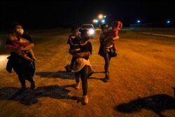 FILE - A group of migrants mainly from Honduras and Nicaragua wait along a road after turning themselves in upon crossing the U.S.-Mexico border, in La Joya, Texas, May 17, 2021.