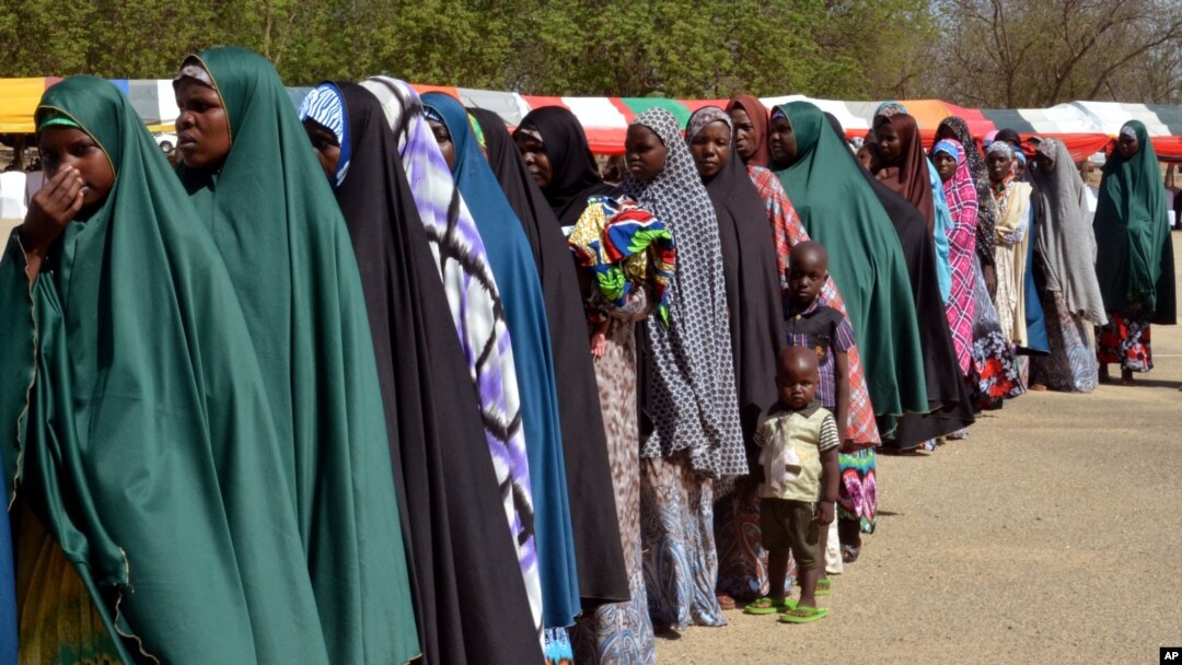 Para perempuan dan anak-anak yang ditahan atas kecurigaan keterlibatan dengan Boko Haram, berbaris saat dibebaskan oleh militer Nigeria di Maiduguri, Nigeria (6/7). (AP/Jossy Ola)