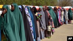 Para perempuan dan anak-anak yang ditahan atas kecurigaan keterlibatan dengan Boko Haram, berbaris saat dibebaskan oleh militer Nigeria di Maiduguri, Nigeria (6/7). (AP/Jossy Ola)