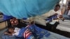 FILE—A child suffering from malaria sleeps under a mosquito net while a mother feeds her child, also suffering from malaria, in the Siaya hospital in Western Kenya, October 30, 2009.