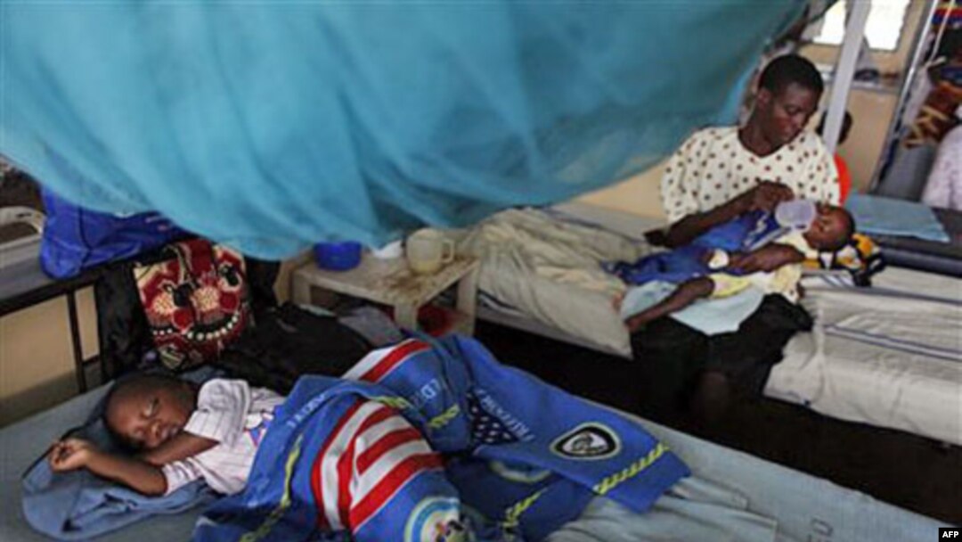 A child suffering from malaria sleeps under a mosquito net while a mother feeds her child, also suffering from malaria, in the Siaya hospital in Western Kenya, October 30, 2009 (file photo)
