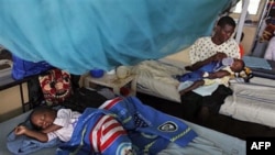 FILE—A child suffering from malaria sleeps under a mosquito net while a mother feeds her child, also suffering from malaria, in the Siaya hospital in Western Kenya, October 30, 2009.