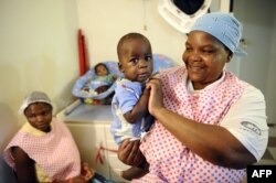 FILE - A nurse plays with an orphan in Bulembu, Swaziland, March 1, 2012.