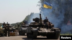 FILE - A Ukrainian army tanks moves past a checkpoint in eastern Ukraine.