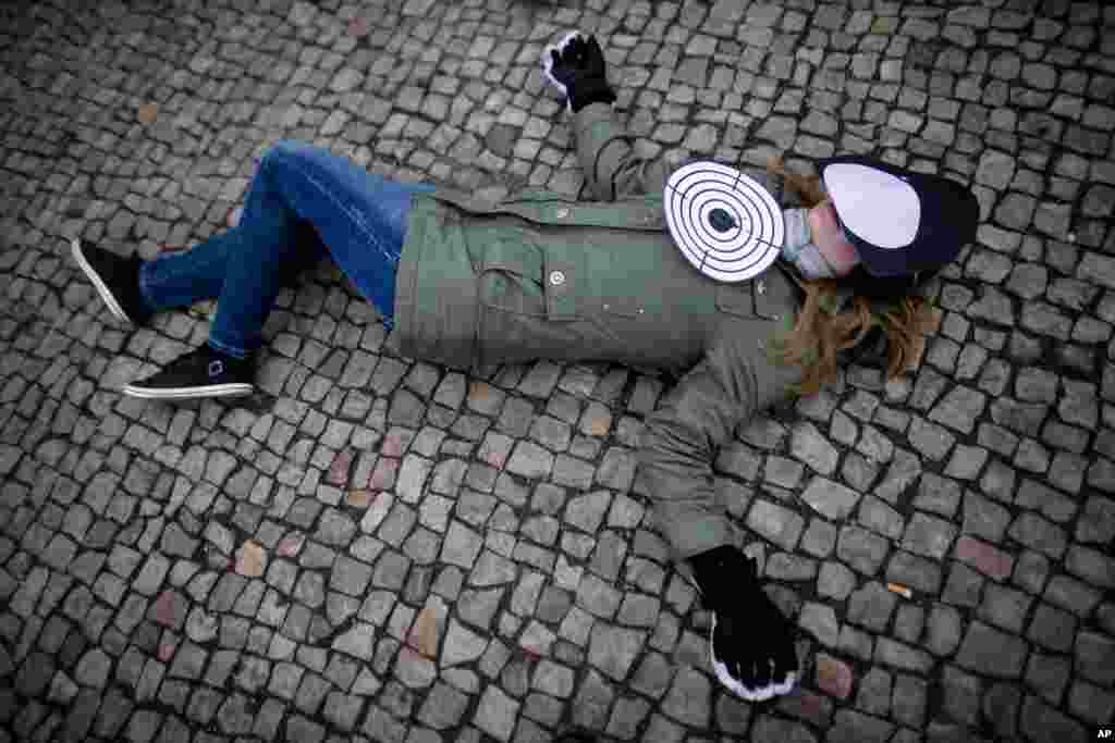 2013年3月8日，国际特赦组织一名女性活动人士在德国柏林国际妇女节示威活动期间躺倒在地，她的胸前放着一个靶子，脸上盖着一幅无脸面具。