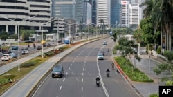 Cars and motorcycles are seen on Sudirman street that is usually busy with traffic, at the main business district in Jakarta, Indonesia, Monday, Sept. 14, 2020. Indonesia's capital on Monday begins to reimpose large-scale social restrictions to control a 