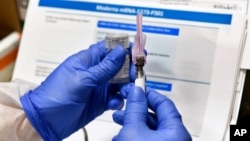FILE - A nurse prepares a shot that is part of COVID-19 vaccine developed by the National Institutes of Health and Moderna Inc., in Binghamton, New York, July 27, 2020. 