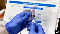 FILE - A nurse prepares a shot that is part of COVID-19 vaccine developed by the National Institutes of Health and Moderna Inc., in Binghamton, New York, July 27, 2020. 
