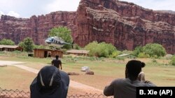 A helicopter lands to rescue people from flooding on the Havasupai reservation in Supai, Ariz., July 12, 2018. Rescue workers were evacuating about 200 tourists Thursday who were caught in flash flooding at a popular campground on tribal land near the Grand Canyon where visitors go to see towering blue-green waterfalls.