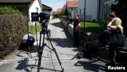 TV crews perpare for a statement in front of a house in Wuerenlingen, Switzerland, where several people were killed late Saturday, May 10, 2015. 