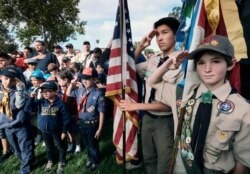 FILE - Boy Scouts and Cub Scouts salute the flag during a ceremony at the Los Angeles National Cemetery in Los Angeles, May 26, 2018.