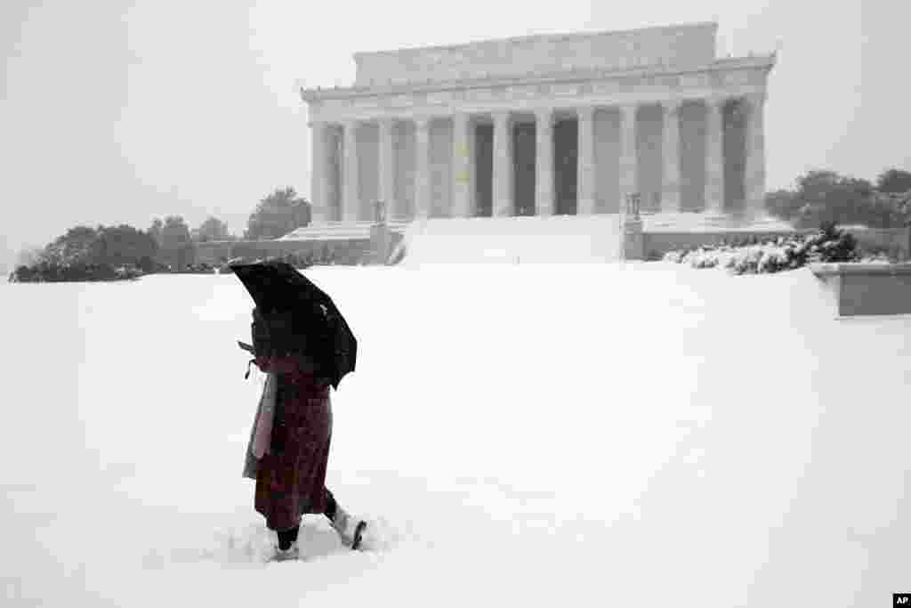 یک زن در برف سنگین از مقابل ساختمان یادبود لینکلن عبور می کند.